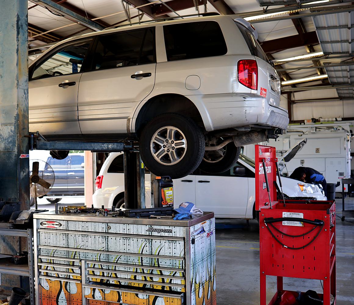 An SUV up on a lift next to the tool chests